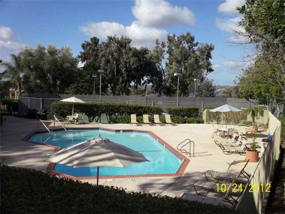 Outdoor swimming pool area with lounge chairs and umbrellas.