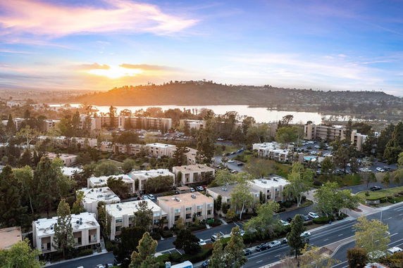 Aerial view of residential buildings with a lake and hills in the background during sunset.