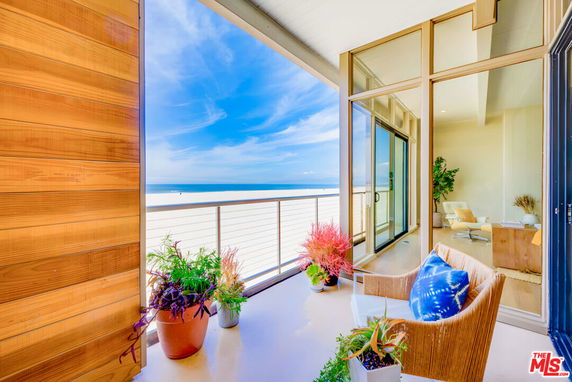Beachfront balcony view with seating and potted plants overlooking the ocean.