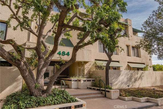 Front view of a multi-story building with a prominent entryway and trees surrounding it.