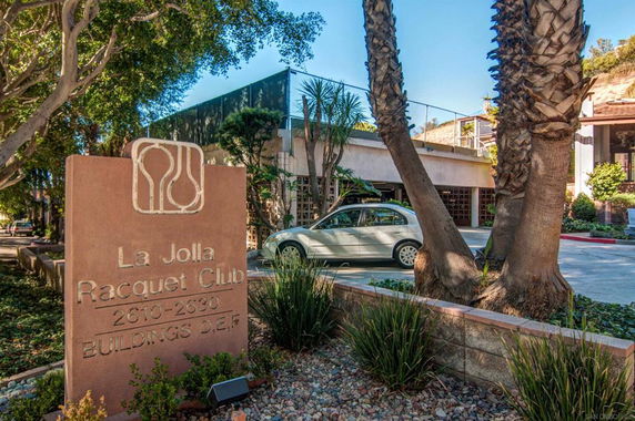 Outdoor parking area at La Jolla Racquet Club with a visible sign and surrounding trees.