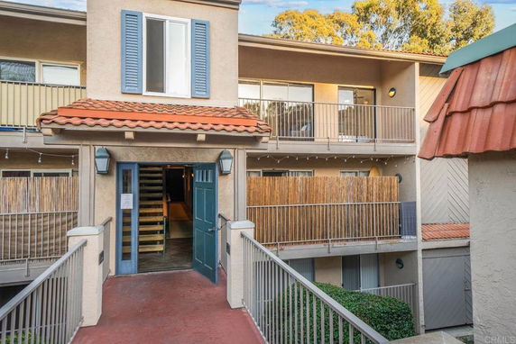 Front view of a multi-story residential building with open balconies and a tiled roof.