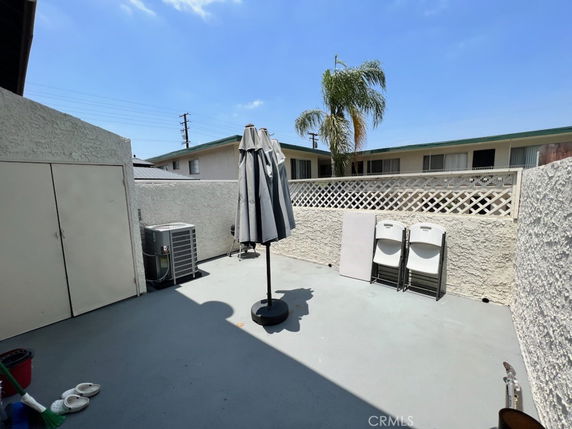 Outdoor area with a concrete floor, standing umbrella, and storage shed.