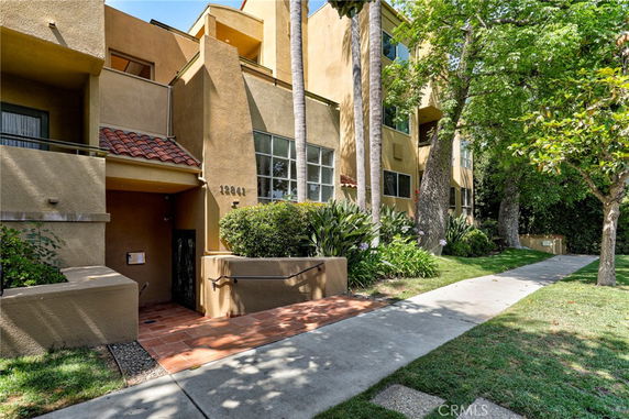 Front view of a multi-story building with stucco exterior and a walkway leading to the entrance.