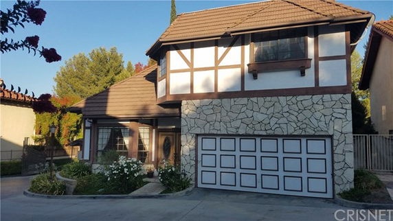 Front view of a two-story house with a stone and wood facade and a double garage.