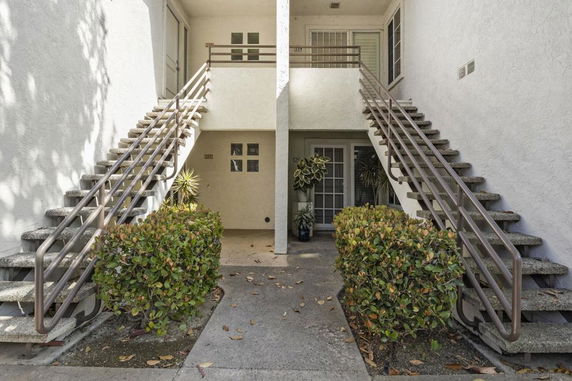 Entrance view of a building with dual staircases and greenery.