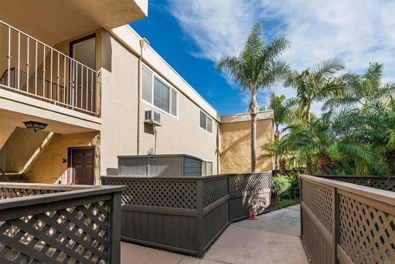 Front view of a building with stucco walls, a balcony, and a fenced walkway.