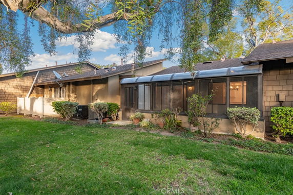 Rear view of a single-story house with a sunroom and garden area.