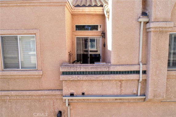 Front view of a stucco house with a small balcony and windows.
