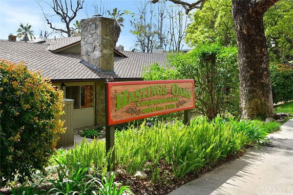 Front view of a condominium with a stone chimney and wooden signage.