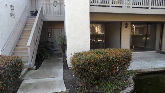 Front view of a multi-story building with an exterior staircase and sliding glass doors.