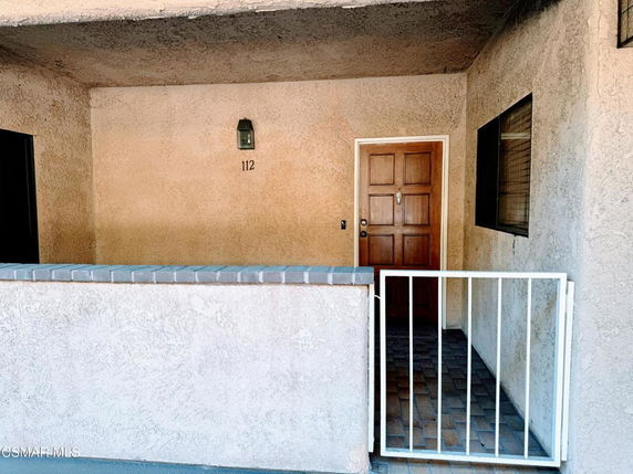 Entrance of a building unit with a closed door and a small gated patio.