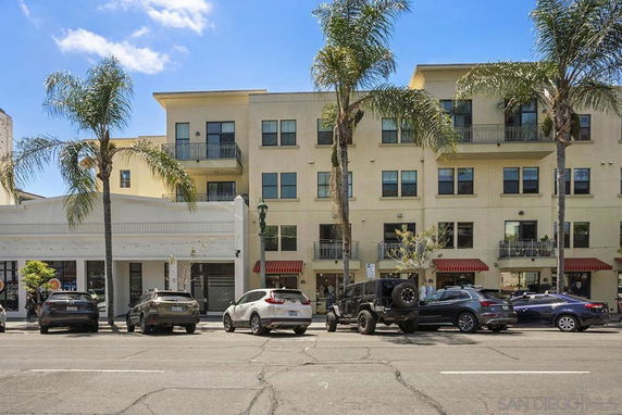 Front view of a multi-story building with balconies and palm trees.