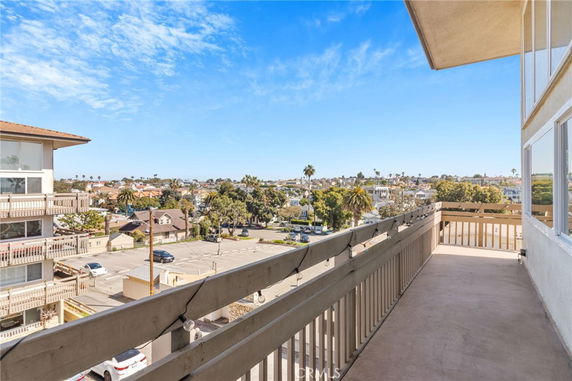 Panoramic view from a balcony overlooking a residential area and distant buildings.