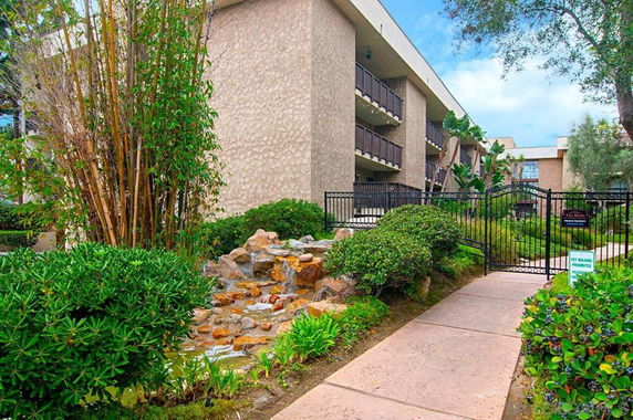 Front view of a multi-story apartment building with balconies and a gated entrance.