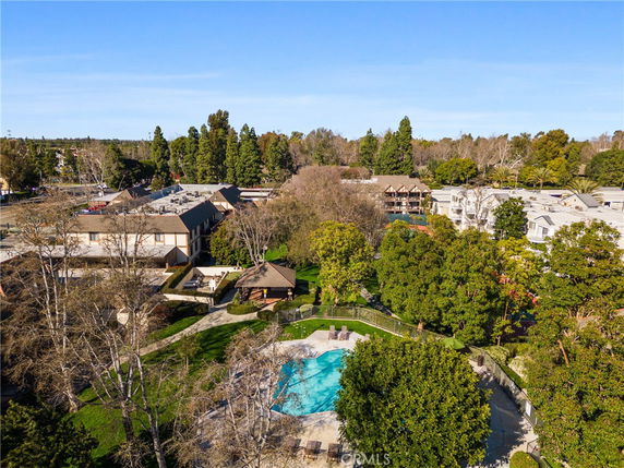 Aerial view of a swimming pool surrounded by trees and residential buildings.