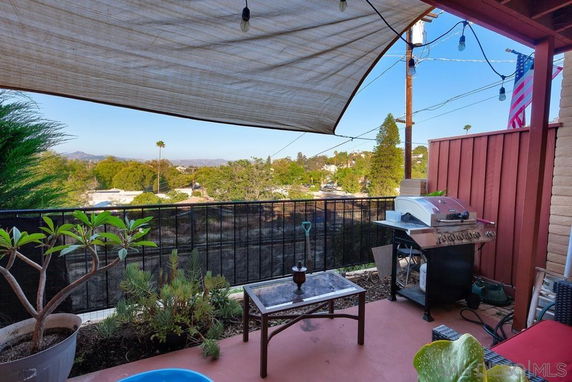 Outdoor patio area with a barbecue grill and a partial view of surrounding landscape.