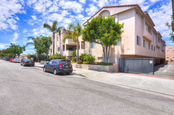 Front view of a multi-story residential building with gated parking area.