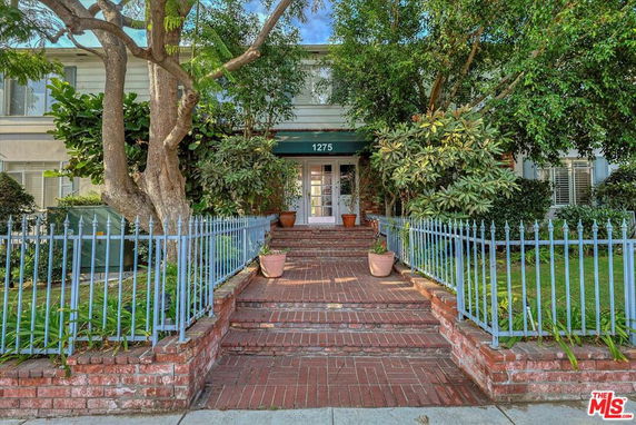 Front view of a house with brick steps and a metal fence.