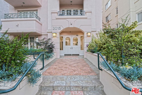 Front view of a multi-story building entrance with double doors and balconies.