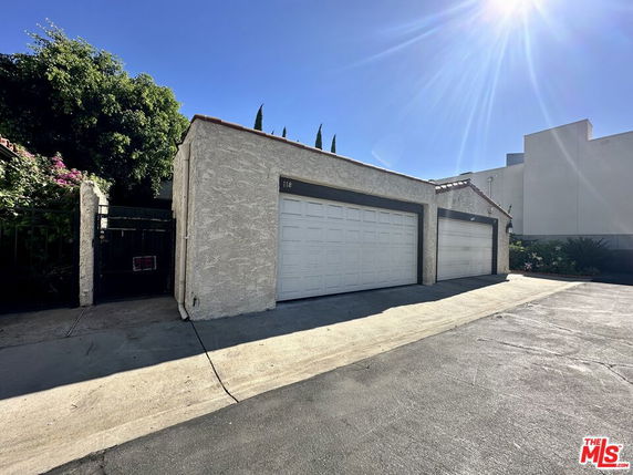 Front view of a building with three white garage doors and a gated entrance.