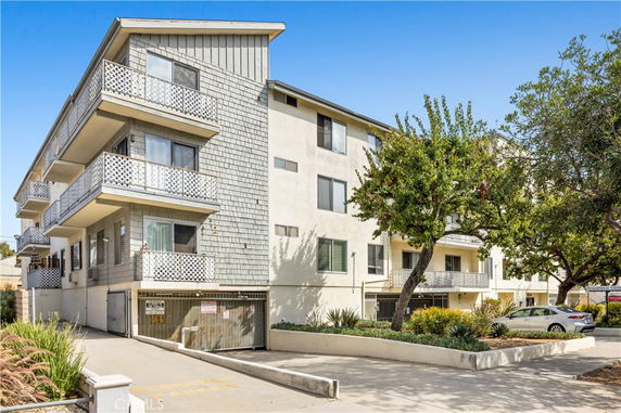 Front view of a multi-story apartment building with balconies and a garage entrance.