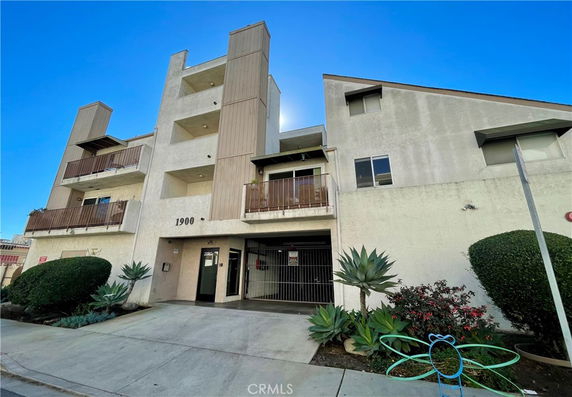 Front view of a multi-story building with balconies and a gated entrance.
