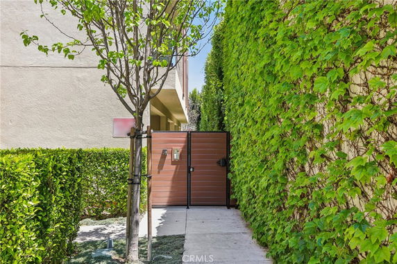 Front entrance view of a building with a modern gate and wall covered in greenery.