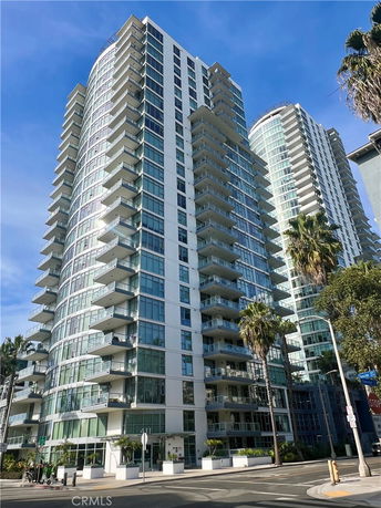 Front view of a multi-story modern apartment building with numerous balconies and glass windows.