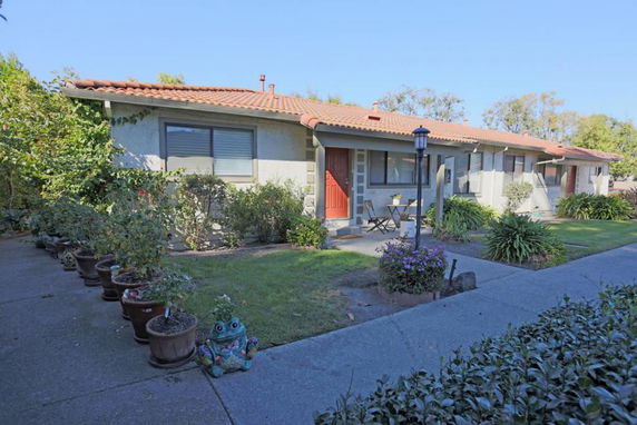 Front view of a single-story house with a red tile roof and a small garden area.