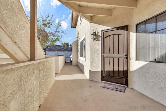 Exterior walkway leading to a front entrance with a wooden door.