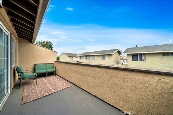 View from a balcony showing neighboring houses and a clear sky.