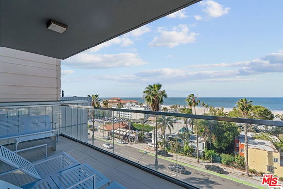 Balcony view overlooking the ocean and palm trees.