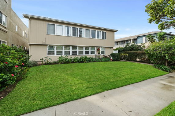 Front view of a two-story house with beige siding and a green lawn.