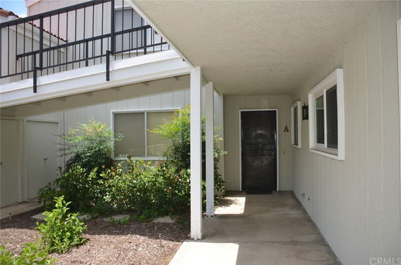 Entrance area of a residential building with a covered walkway and plants.