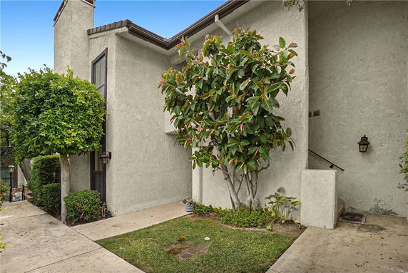 Front view of a two-story house with textured exterior walls and greenery.