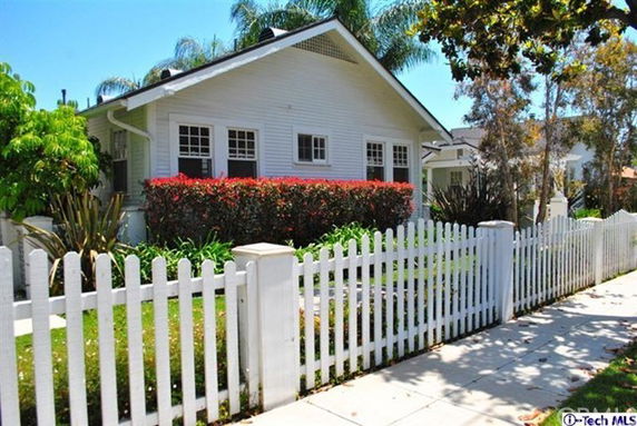 Front view of a single-story house with white siding and a white picket fence.