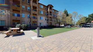 Front view of a multi-story apartment building with balconies and a paved courtyard.