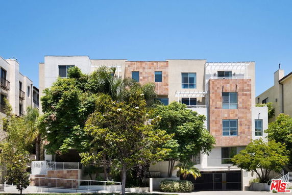 Front view of a modern multi-story building with a mixture of brick and stucco facade.
