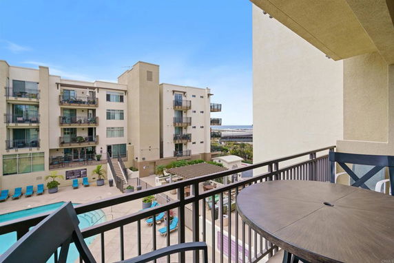 View from a balcony overlooking apartment buildings and a swimming pool.