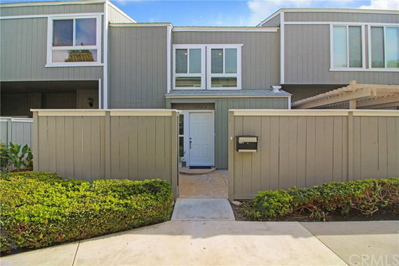 Front view of a two-story house with a fenced entrance and gray exterior.
