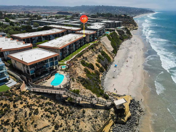 Aerial view of a beachside building complex with swimming pool and proximity to the ocean.