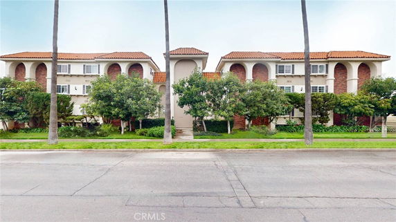 Front view of a multi-story building with red-tiled roof and archway design elements.