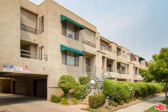 Front view of a multi-story apartment building with balconies and a staircase.