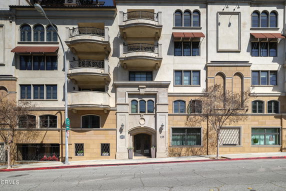 Front view of a multi-story building with balconies and arched windows.