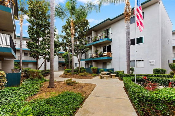 Front view of a multi-story apartment building with balconies and landscaped grounds.