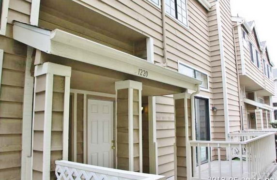 Front view of a multi-story townhouse with wooden siding and balconies.