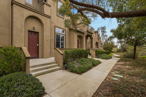 Front view of a row of townhouses with red doors and small steps leading to each entrance.