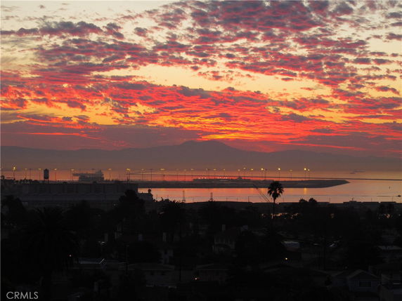 Panoramic view of a coastal city during a vibrant sunset.