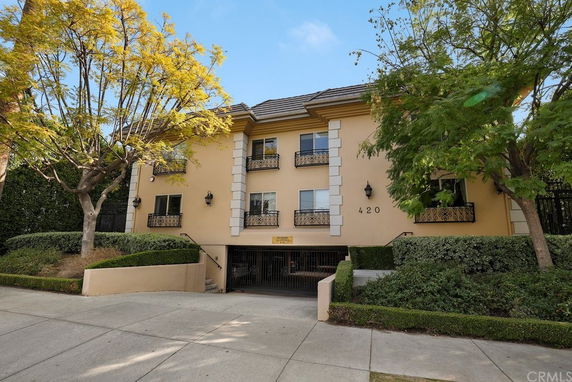 Front view of a multi-story building with decorative balconies and a gated entrance.